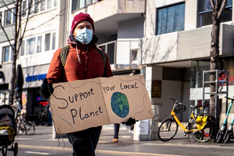A man holding a 'save your local planet' sign