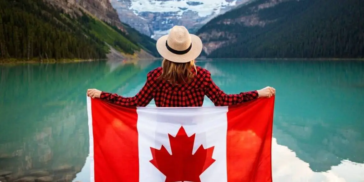 Woman draped in a Canadian flag in front of a lake