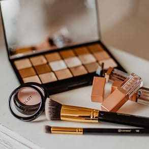 Makeup palette and brushes on a table with a small mirror